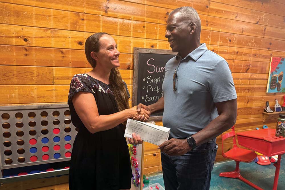 Tara Forgette receives a check from Sierra Pacific Industries to help with the needed repairs on building.